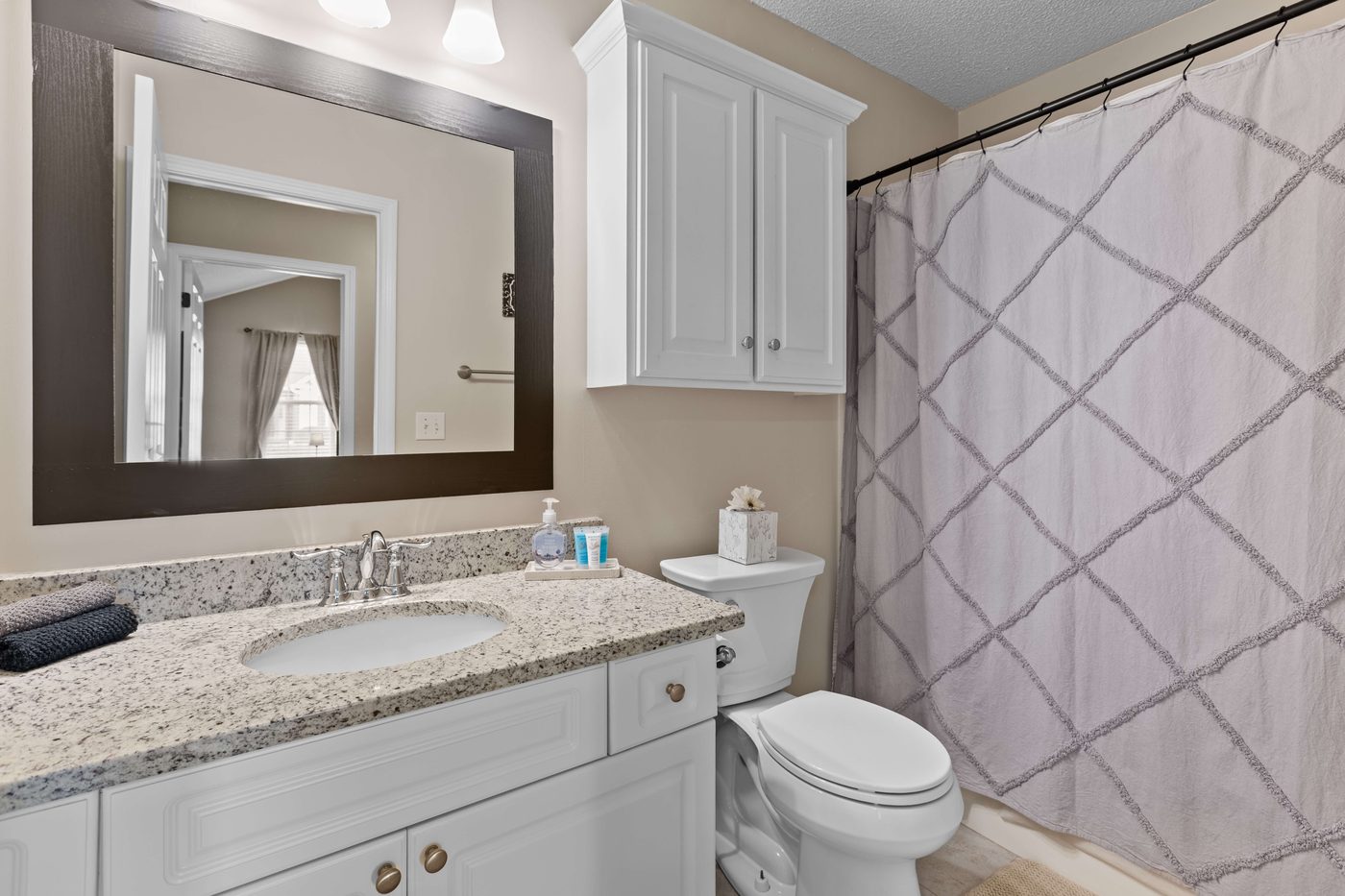 Second full bathroom with a granite topped vanity, framed mirror, and a tub and shower combination