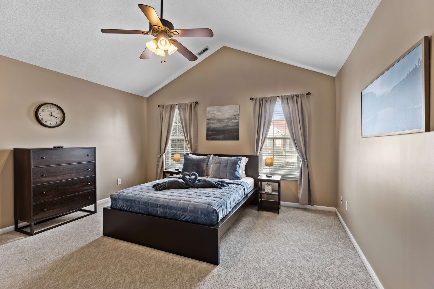 Second bedroom with a queen bed under a vaulted ceiling and a lighted ceiling fan