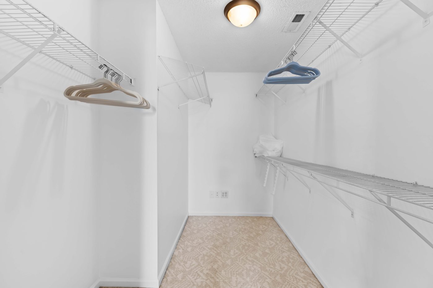 Bedroom walk-in closet with wire shelving on two walls and a tile floor