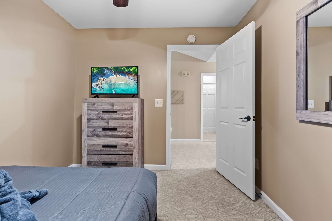 Third bedroom with a dresser, a wall mounted TV, and a doorway to the hall