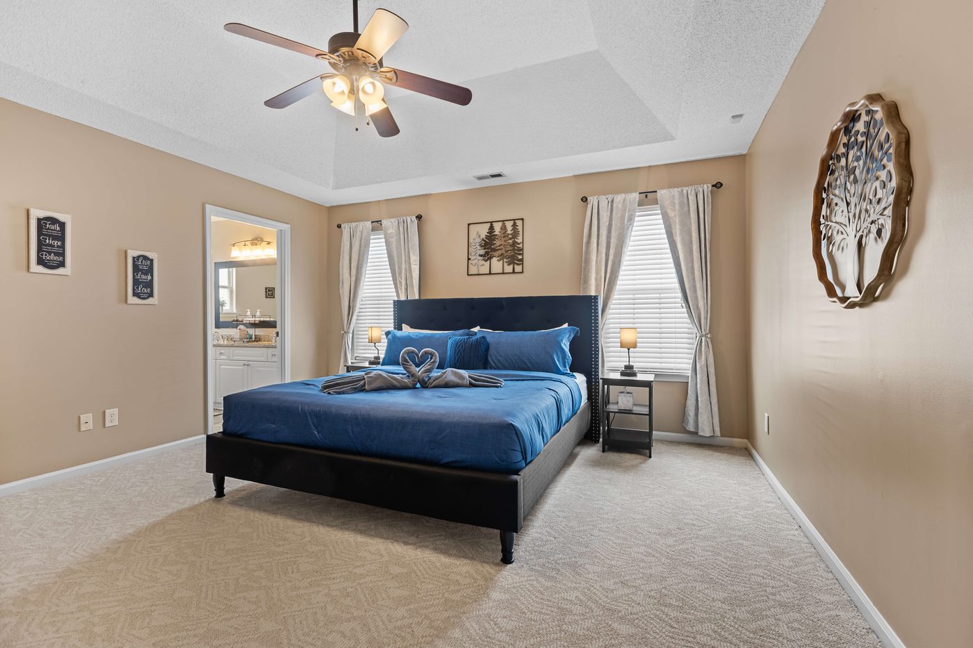 Primary bedroom with a king bed, a tray ceiling, and a lighted ceiling fan