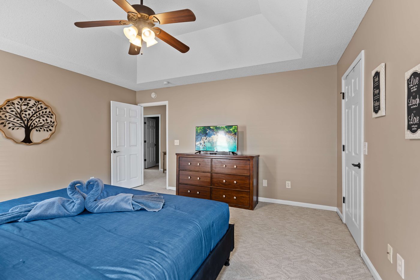 Primary bedroom with a dresser, a wall mounted TV, and closet storage