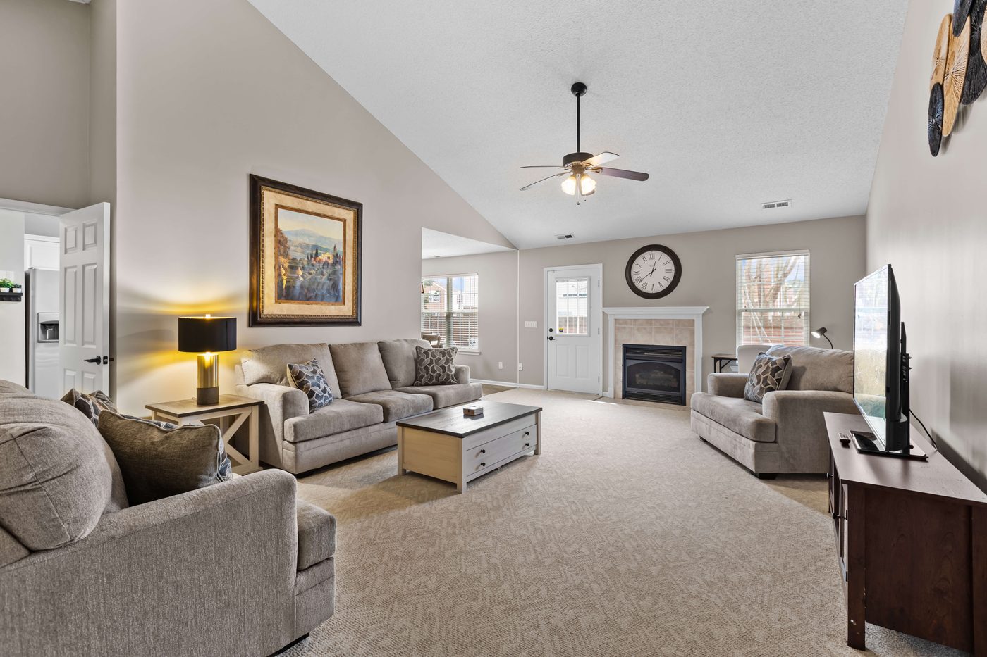Living room with a tiled gas fireplace, three sofas, and a vaulted ceiling