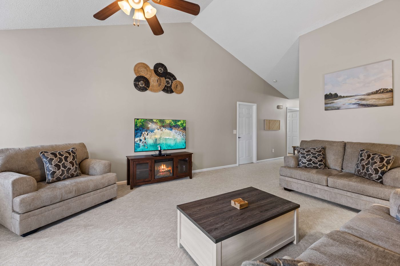 Living room seating area with a wall mounted TV and a vaulted ceiling