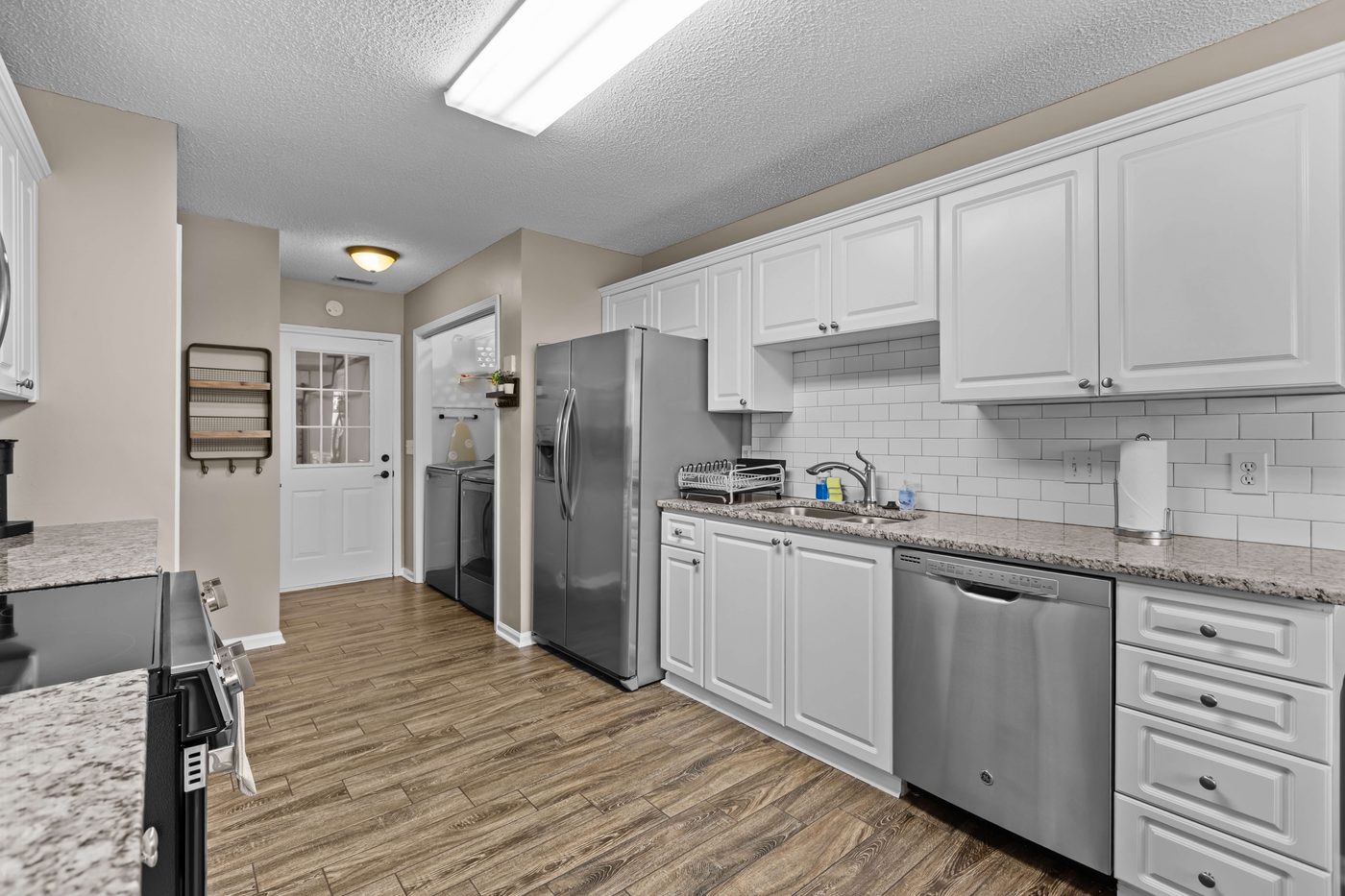 Kitchen with white cabinetry, granite counters, and stainless steel appliances